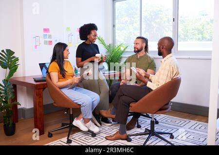 Four diverse team members having informal meeting, sitting in creative office Stock Photo