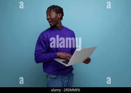 surprised american young brunette man with dreadlocks with laptop Stock Photo