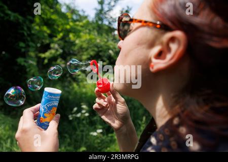 Stuttgart, Germany. 24th May, 2023. A woman blows soap bubbles with a Pustefix brand toy. Pustefix celebrates its 75th anniversary this year. The company became famous with soap bubble toys made in Germany. But the market is fiercely competitive in the industry. Credit: Julian Rettig/dpa/Alamy Live News Stock Photo