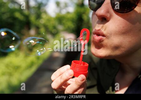 Stuttgart, Germany. 24th May, 2023. A woman blows soap bubbles with a Pustefix brand toy. Pustefix celebrates its 75th anniversary this year. The company became famous with soap bubble toys made in Germany. But the market is fiercely competitive in the industry. Credit: Julian Rettig/dpa/Alamy Live News Stock Photo