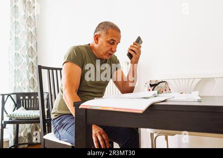 Portrait man working on laptop, making notes in notebook, at home Stock Photo