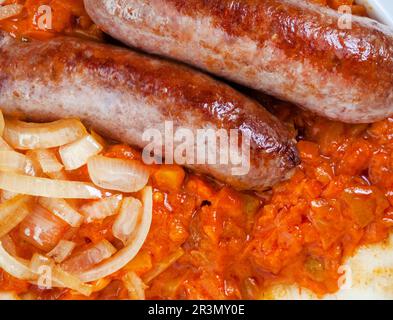 close up of Traditional South African Pap and Wors, sausage with popular maize meal staple covered with Chakalaka or relish Stock Photo