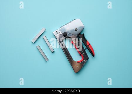 Household manual stapler and staples on a blue background, top view Stock Photo