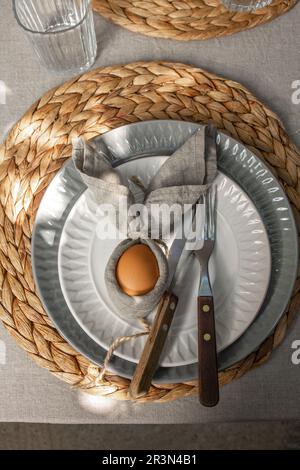 Festive Easter table setting. Funny Easter bunny made of egg and linen napkin on plate. Gray background Stock Photo