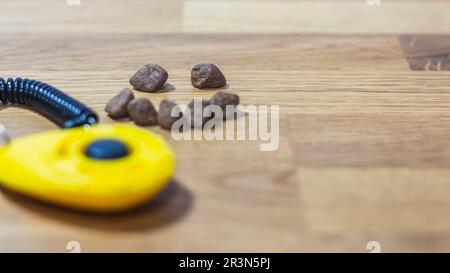 A yellow dog training clicker with treat kibble arranged in a smiley face Stock Photo