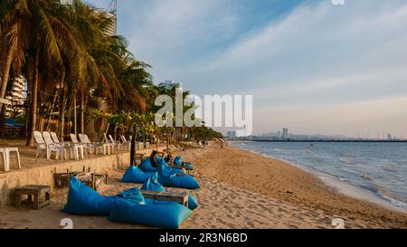 Sunset at a tropical beach with palm trees. Pattaya Thailand, people relaxing in front of a restaurant at the beach Stock Photo