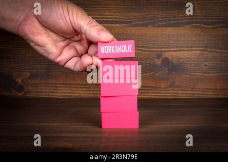 Workaholic Concept. Colorful blocks in a pile on a wooden texture background. Stock Photo