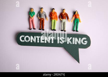 CONTENT IS KING CONCEPT. Miniature human figures and speech bubble on a white background. Stock Photo