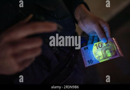 Stuttgart, Germany. 24th May, 2023. A police officer uses his new lamp to check the authenticity of a banknote, for example, with the help of UV light during an operation. The Southwest Police will be getting these new lamps for use from now on. Credit: Christoph Schmidt/dpa/Alamy Live News Stock Photo