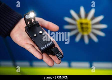 Stuttgart, Germany. 24th May, 2023. A policewoman presents the new lamp for the task forces of the Southwest Police in front of the coat of arms of the Baden-Württemberg State Police. Credit: Christoph Schmidt/dpa/Alamy Live News Stock Photo