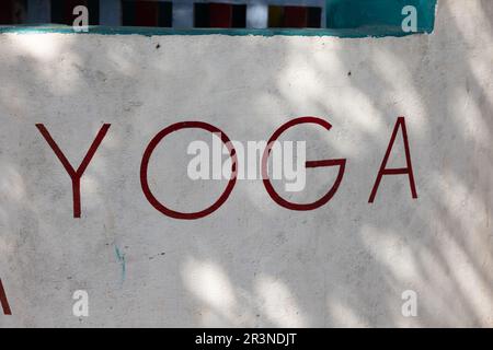 A sign of the word yoga hangs on the wall, white text letters, meditation, fitness room, voluminous printed letters. High quality photo Stock Photo