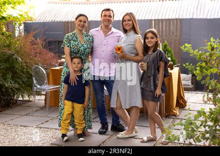 Family participates in the organization of dinner. Family of five members setting dining table Stock Photo