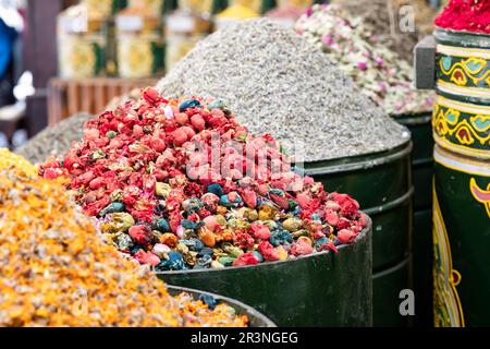 Heaped metal cans filled with colourful dried flowerheads and other herbs outside a herbal remedy souk in Marrakesh Medina, Morocco. Stock Photo