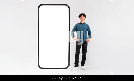 Man Standing Near Huge Cellphone Empty Screen On White Background Stock Photo