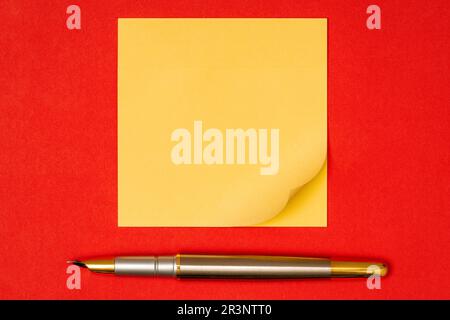 Fountain pen and blank sticky note on red background waiting for your message Stock Photo