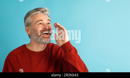 Happy middle aged man holding hand next to mouth, screaming Stock Photo