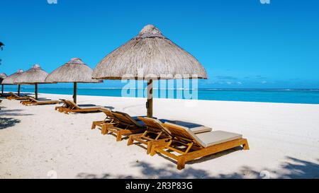 Tropical beach with palm trees and white sand blue ocean and beach beds with umbrella in Mauritius Stock Photo