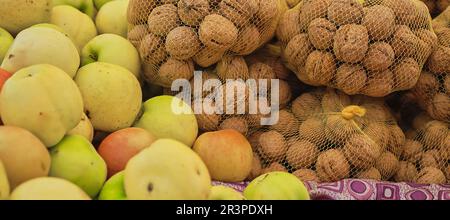 Walnuts and apples on the counter at the farmers market, selective focus on ripe produce, showcase in groceries Stock Photo