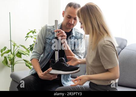 Modern Hospital Physical Therapy: Doctor Uses Tablet Computer, Helps Disabled Patient with Injury Walk on Treadmill Wearing Advanced Robotic Stock Photo