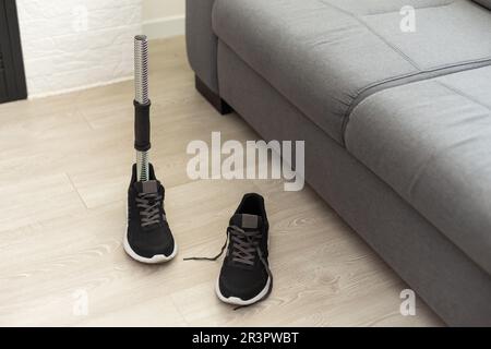 prosthetic leg disability on above knee transfemoral leg prosthesis artificial device stands on feet on floor, close up.  Stock Photo