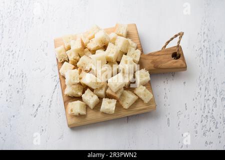 Wooden board with diced bread, croutons cooking on light blue tabletop, top view Stock Photo