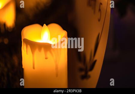 Close up of classic candle with orange flames burning on Stock Photo