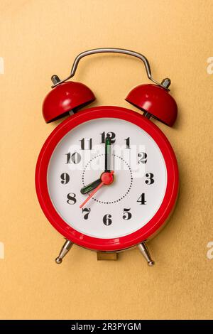 Red alarm clock lying on the golden background Stock Photo