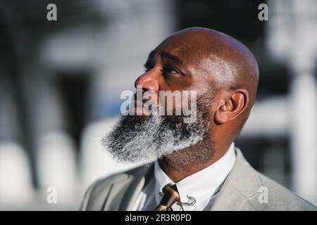 A close-up portrait of the profile of a charming black man with a long greying beard, dressed in a grey suit jacket, captured with selective focus, hi Stock Photo