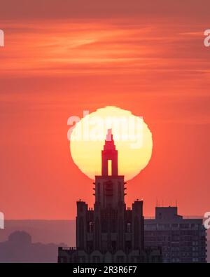 Huge sun setting between New York City towers Stock Photo - Alamy