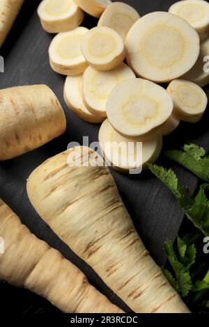 Whole and cut parsnips on wooden board, above view Stock Photo