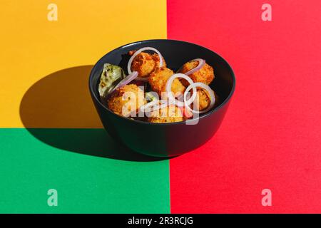 Salad with deep-fried cheese balls and red onions. Hard light, deep shadow Stock Photo