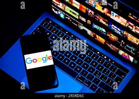 ITALY - May 24, 2023: Netflix homepage on a Mac laptop screen and the Google logo on the smartphone screen. Netflix is an online video streaming Stock Photo