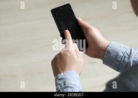 Man holding damaged smartphone indoors, closeup. Device repairing Stock Photo