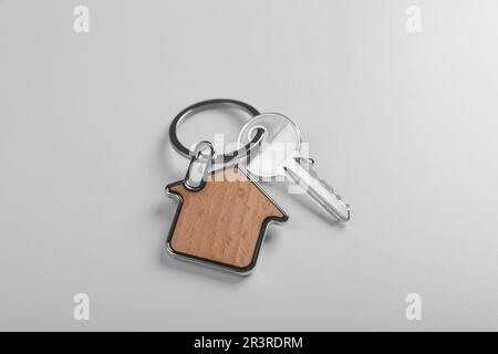 Key with trinket in shape of house on white background, above view. Real estate agent services Stock Photo