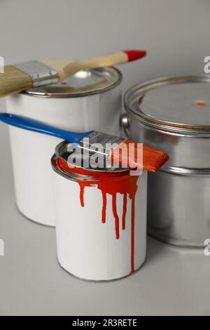 Cans of orange paint and brushes on grey background Stock Photo