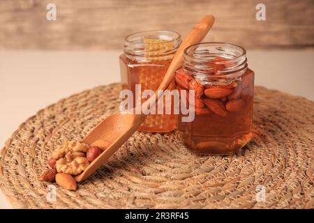 Jars with honey and different nuts on beige table Stock Photo