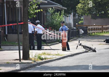 Philadelphia, Pennsylvania, United States, May 24, 2023. Police officers from the Philadelphia police department put up crime scene tape and secure the crime scene. Two people shot, one person pronounced dead in a shooting in broad daylight in Philadelphia, Pennsylvania, United States on May 24, 2023. At 2:51 PM Eastern Time, Wednesday afternoon at the intersection of West Susquehanna Avenue and North Gratz Street, a 31-year-old black male was shot one time in the left arm, one time in the left side and one time in the back and was transported to the hospital by private automobile, he was late Stock Photo