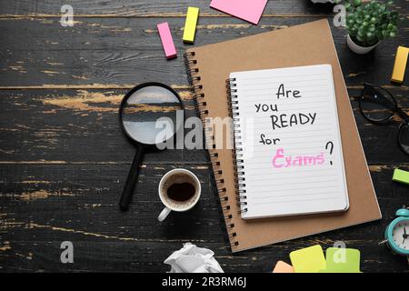 Notebooks with question ARE YOU READY FOR EXAM?, cup of coffee and magnifier on black wooden background Stock Photo