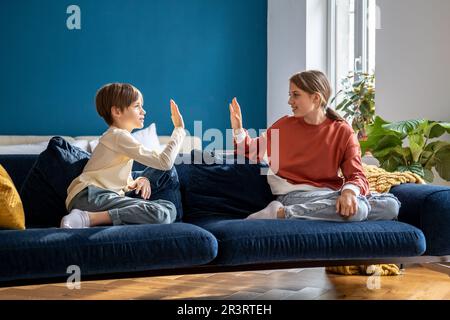 Happy children siblings giving high five to each other, brother and sister bonding together at home Stock Photo