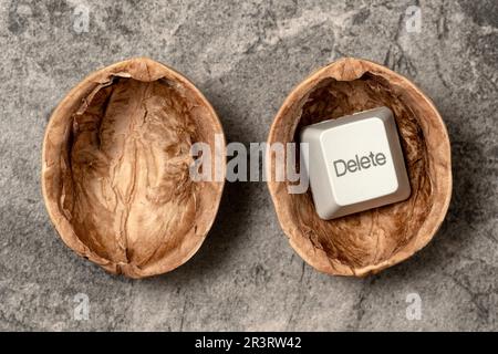 Opened walnut shell with a DELETE key of computer keyboard Stock Photo