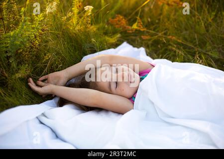 Girl sleeps on bed in grass, Sweet stretches and yawns sleepily, good morning in fresh air. Eco-friendly, healthy sleep, Protect Stock Photo