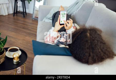 Back view of african american millennial woman holding smartphone, Stock Photo