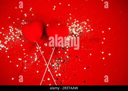 Two decorative hearts on a stick with ribbon. Bright background with silver sequins and round confetti. Stock Photo