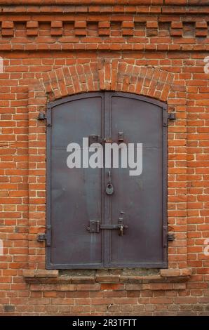 Historical old closed metal window shutter in brick wall Stock Photo