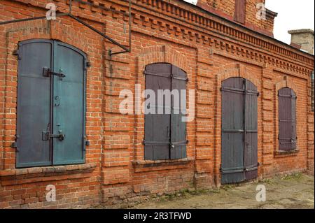 Historical old closed metal windows shutter in brick wall Stock Photo