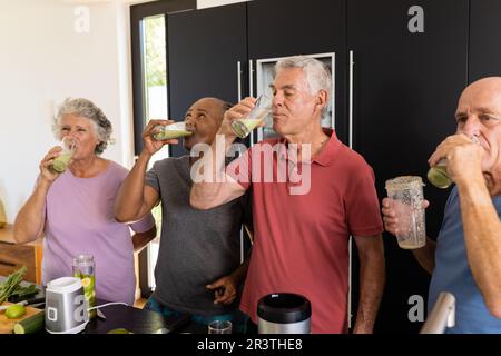 Happy diverse senior friends drinking healthy smoothies together in kitchen Stock Photo