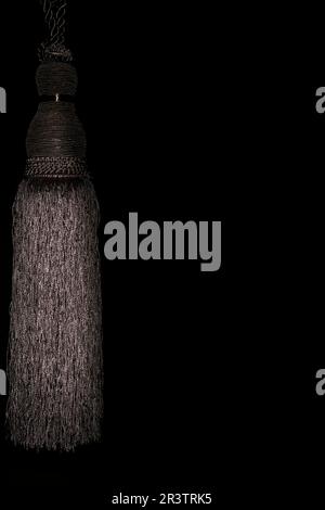 Black rope tassel with fringes, texture background, studio photography Stock Photo