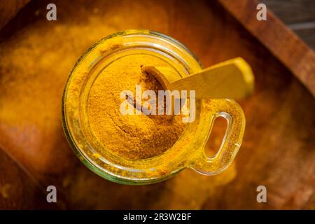 Ground turmeric in a glass jar on wooden background Stock Photo