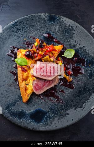 Traditional roasted Italian panettone tagliata di manzo with sliced beef steak and vegetable served as close-up on a Nordic desi Stock Photo