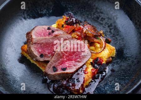 Traditional roasted Italian panettone tagliata di manzo with sliced beef steak and vegetable served as close-up on a Nordic desi Stock Photo